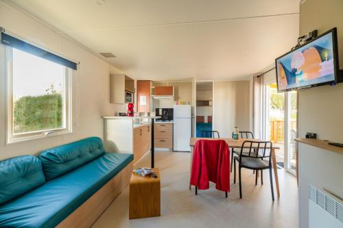 Il comprend un salon avec un canapé bleu et une cuisine. dans l'établissement Camping Les Carolins, à Saint-Lo-dʼOurville