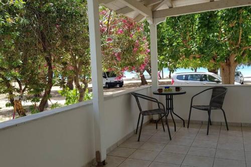 a porch with two chairs and a table and trees at Lovely Sunrise apartment by the beach in Methoni
