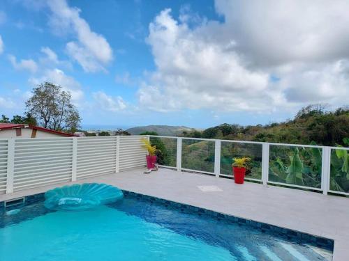 - une piscine sur une terrasse à côté d'une clôture dans l'établissement Bold'Air piscine, vue mer, au Vauclin