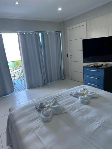 a bedroom with a white bed with two white bows at Residência Angra Deep Blue in Angra dos Reis