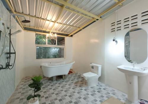 a bathroom with a tub and a toilet and a sink at แม่ไพโฮมสเตย์ ล่องแพกอนโดล่า in Ban Racha Tai