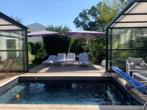 een zwembad met stoelen en een parasol in de achtertuin bij Villa 37 in Courrejean