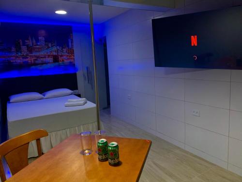 um quarto com uma mesa, uma televisão e uma cama em Hotel dos PRAZERES (Motel) no Recife