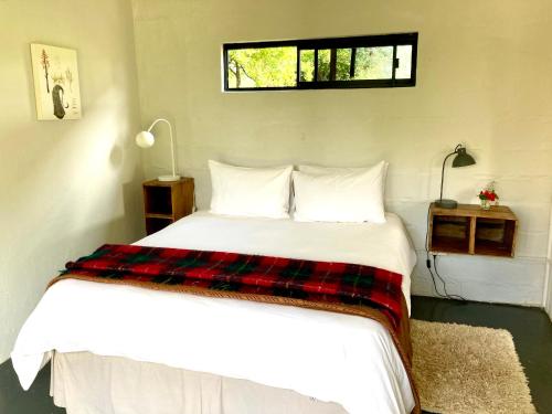 1 dormitorio con cama blanca y manta a cuadros en 180 at Mission House en Curryʼs Post