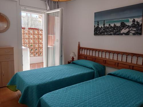 エンプリアブラバにあるPrecioso Apartamento Gran Reservaのベッドルーム1室(ベッド2台、窓付)