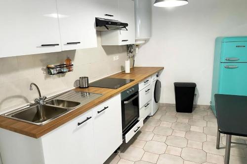 une cuisine avec des armoires blanches, un évier et une cuisinière dans l'établissement maison deux pièces tout confort, à Stains