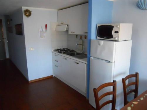 een kleine keuken met een witte koelkast en een magnetron bij Appartamento con piscina e aria condizionata in La Maddalena