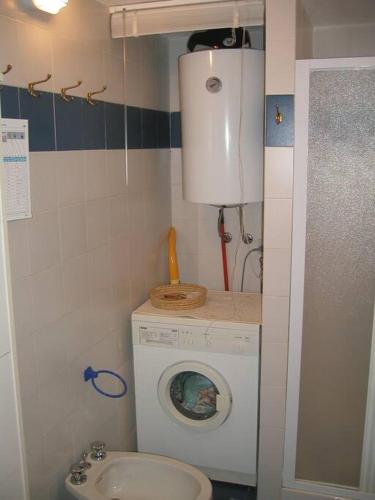 a small bathroom with a washing machine and a sink at Appartamento con piscina e aria condizionata in La Maddalena
