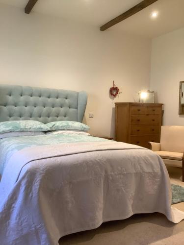 a bedroom with a large bed and a dresser at Orchard Cottage, Clematis cottages, Stamford. Accessible luxury home. in Stamford