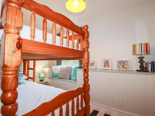 a bedroom with a wooden bunk bed at Bro Tref Cottage in Newquay