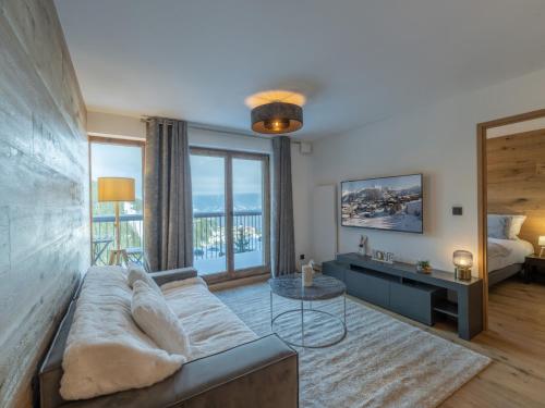 un salon avec un canapé et une grande fenêtre dans l'établissement Appartement Neuf 65m² Courchevel Moriond, 2 Chambres + Cabine, Balcon, Parking Couverts, Skis aux Pieds - FR-1-563-127, à Courchevel