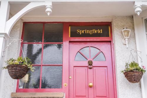 eine rosa Tür auf einem Gebäude mit Körben drauf in der Unterkunft Springfield-Windermere in Windermere