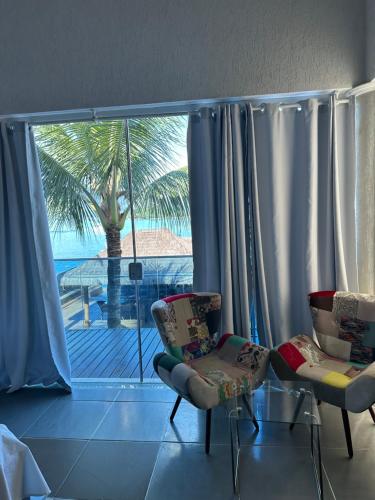 a living room with two chairs and a large window at Residência Angra Deep Blue in Angra dos Reis