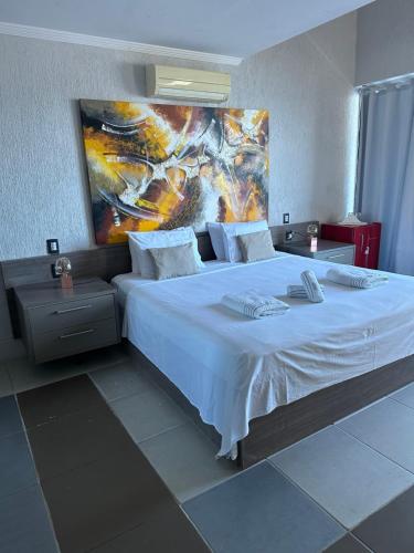 um quarto com uma cama grande e uma pintura na parede em Residência Angra Deep Blue em Angra dos Reis