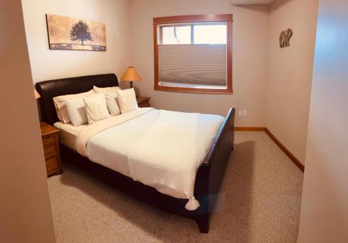 um quarto com uma cama com lençóis brancos e uma janela em Cozy Winter Wonderland Getaway em Canmore