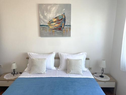 ein Bett mit weißen Kissen und ein Gemälde an der Wand in der Unterkunft Cosy apartment on the Beach - Kali in Kali