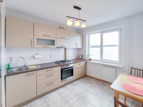 a kitchen with white cabinets and a sink and a table at Apartamentai ramioje vietoje in Šiauliai