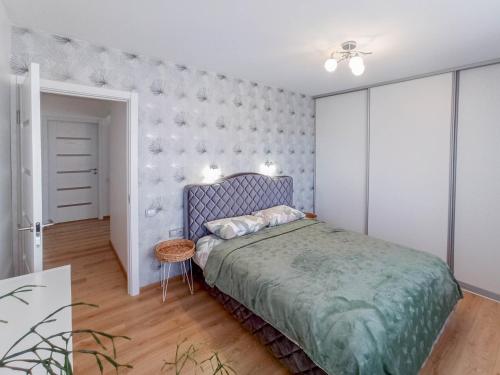 a bedroom with a blue bed and a white wall at Apartamentai ramioje vietoje in Šiauliai