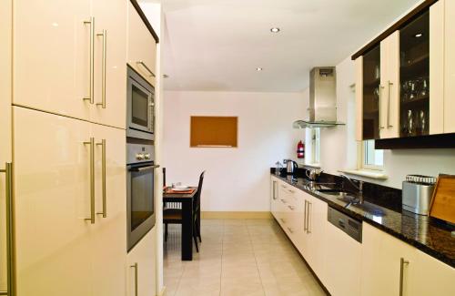a kitchen with white cabinets and a table at Ring Of Kerry Holiday Cottages No 20 by Trident Holiday Homes in Kenmare