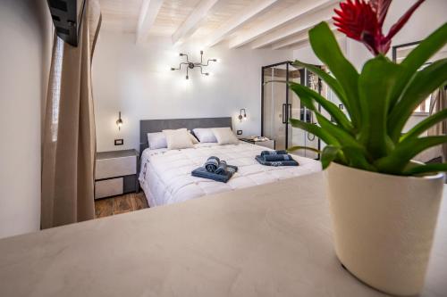 a bedroom with a large white bed and a potted plant at Casa Vacanze RetroScena in Avola