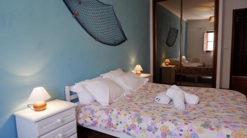 a bedroom with a bed with pillows and a mirror at Casa BARCA DO SOL in Vila Nova de Milfontes