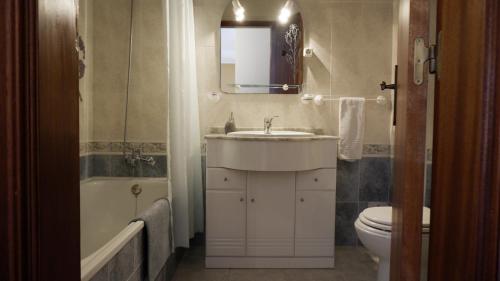 a bathroom with a sink and a toilet and a mirror at Casa BARCA DO SOL in Vila Nova de Milfontes