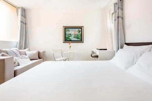 a white bedroom with a large bed and a couch at Rincón Caribeño Habitación Privada in Santo Domingo