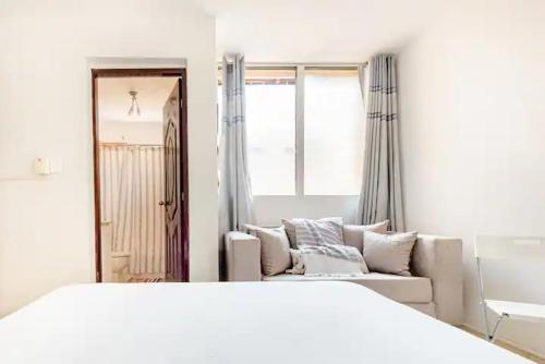 a white room with a couch and a large bed at Rincón Caribeño Habitación Privada en Apartamento in Santo Domingo