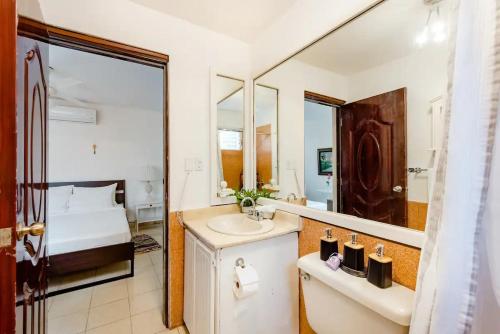 a bathroom with a sink and a bed and a mirror at Rincón Caribeño Habitación Privada in Santo Domingo