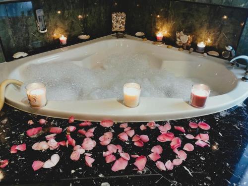 a bath tub filled with pink flowers and candles at Casa das Camélias in Guimarães