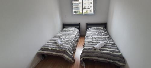 - 2 lits dans une petite chambre avec fenêtre dans l'établissement Ótimo Apto no Centro, perto de tudo!, à Poços de Caldas