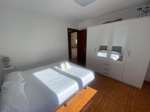 een witte slaapkamer met een bed en een kast bij Piso a 50m de la Playa en Somo con Garaje Privado in Somo