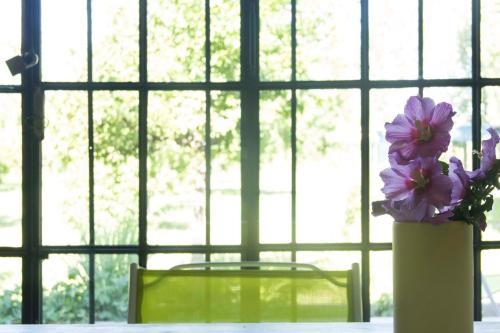 un jarrón con flores púrpuras en una mesa frente a una ventana en Avalenn, Casa de Campo en Tunuyán