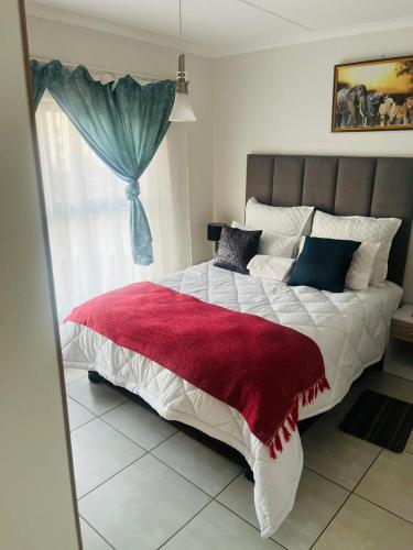 een slaapkamer met een groot bed en een rode deken bij The blyde crystal lagoon in Pretoria
