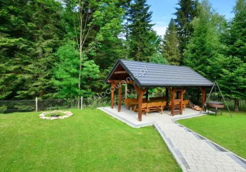 a wooden gazebo with benches in a park at Domki Letniskowe SOBALSKI in Zawoja