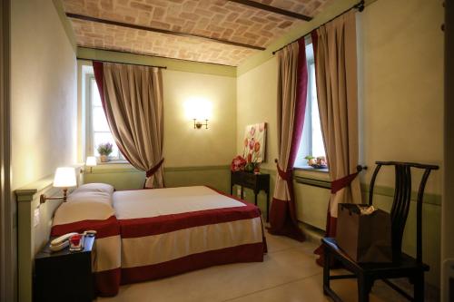 een slaapkamer met een bed en 2 ramen bij NaturalMente Wine Resort in Agliano Terme