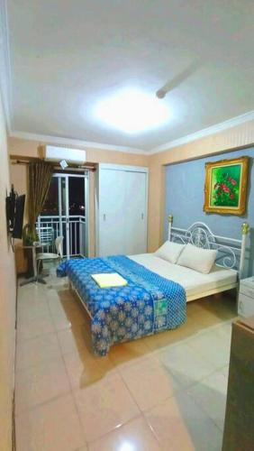 een slaapkamer met een bed met een blauw dekbed bij Bogor Valley Apartment in Bogor