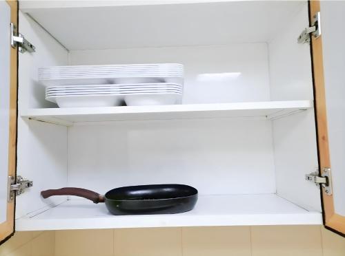 a frying pan and plates on a shelf in a kitchen at MBZ - Relax Room in Unique Flat in Abu Dhabi