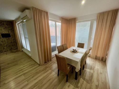 - une salle à manger avec une table, des chaises et des fenêtres dans l'établissement Apartman De lux 85m2, à Bojnice