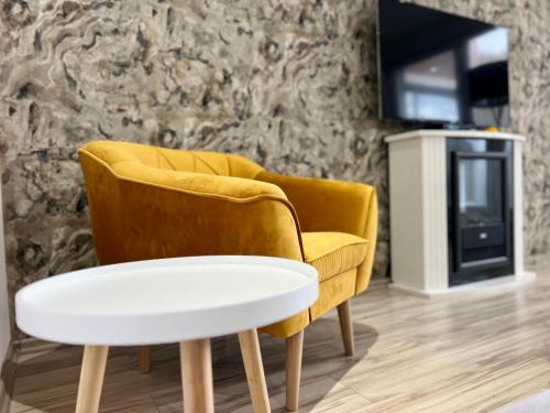 a yellow chair and a white coffee table in a room at Apartman De lux 85m2 in Bojnice