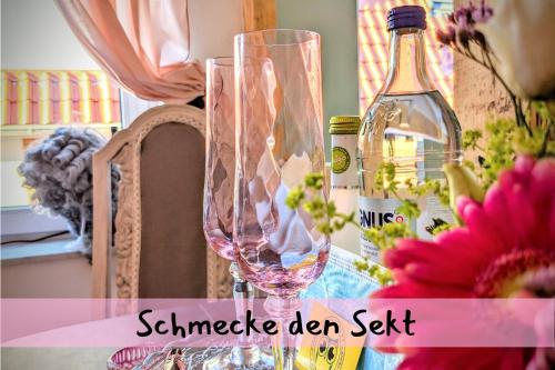a pair of wine glasses sitting on a table with a bottle at Queen Apartment in Uelzen