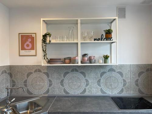 a kitchen with a sink and a shelf with dishes at Apartamenty Cud Miód in Krosno