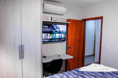 a room with a bed and a sink and a tv at Apartamento Aconchegante próximo ao Shopping Pantanal in Cuiabá