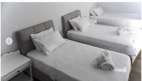 two beds with towels on them in a room at Helios Beach Hotel in Perissa
