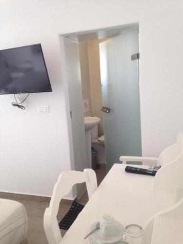 a living room with a white table and a television at Helios Beach Hotel in Perissa