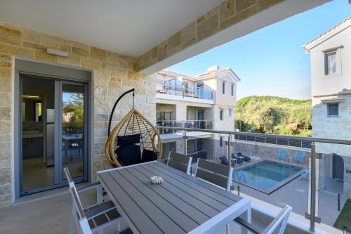 a patio with a wooden table and chairs on a balcony at Momento Luxury Apartments walking distance from the beach in Nikiana