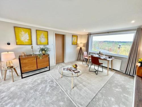 a living room with a desk and a large window at Treetops Cottage at Treetops Hideouts in Richmond