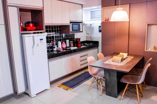 a kitchen with a table and a white refrigerator at Um plus na sua acomodação - LOFT FELAU in Cuiabá