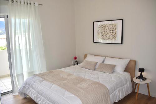 una camera con un letto bianco e una foto appesa al muro di KAPA Central Apartment a Kalamáta