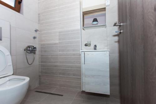 een witte badkamer met toilet en douche bij House Nativa in Mola Kalyva